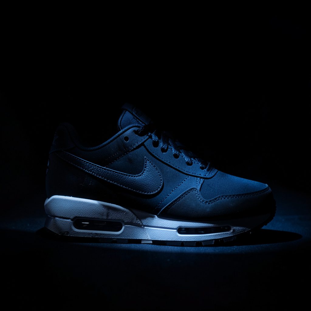 Nike Air Max 1 in diep bordeauxrood met zwarte zool, gestileerd neergezet op een donkere ondergrond