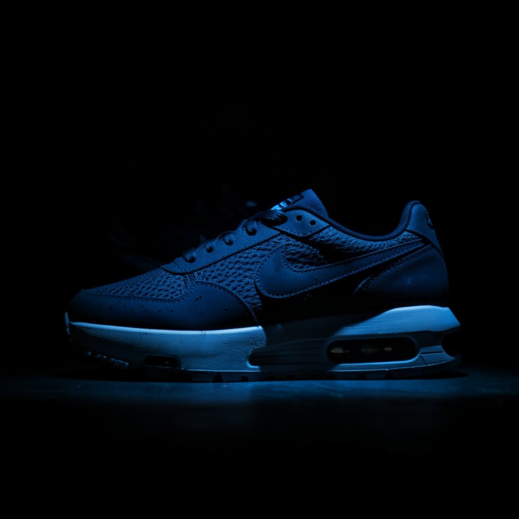 Nike Air Max sneaker in lichte kleuren op een donkere, schaduwrijke achtergrond