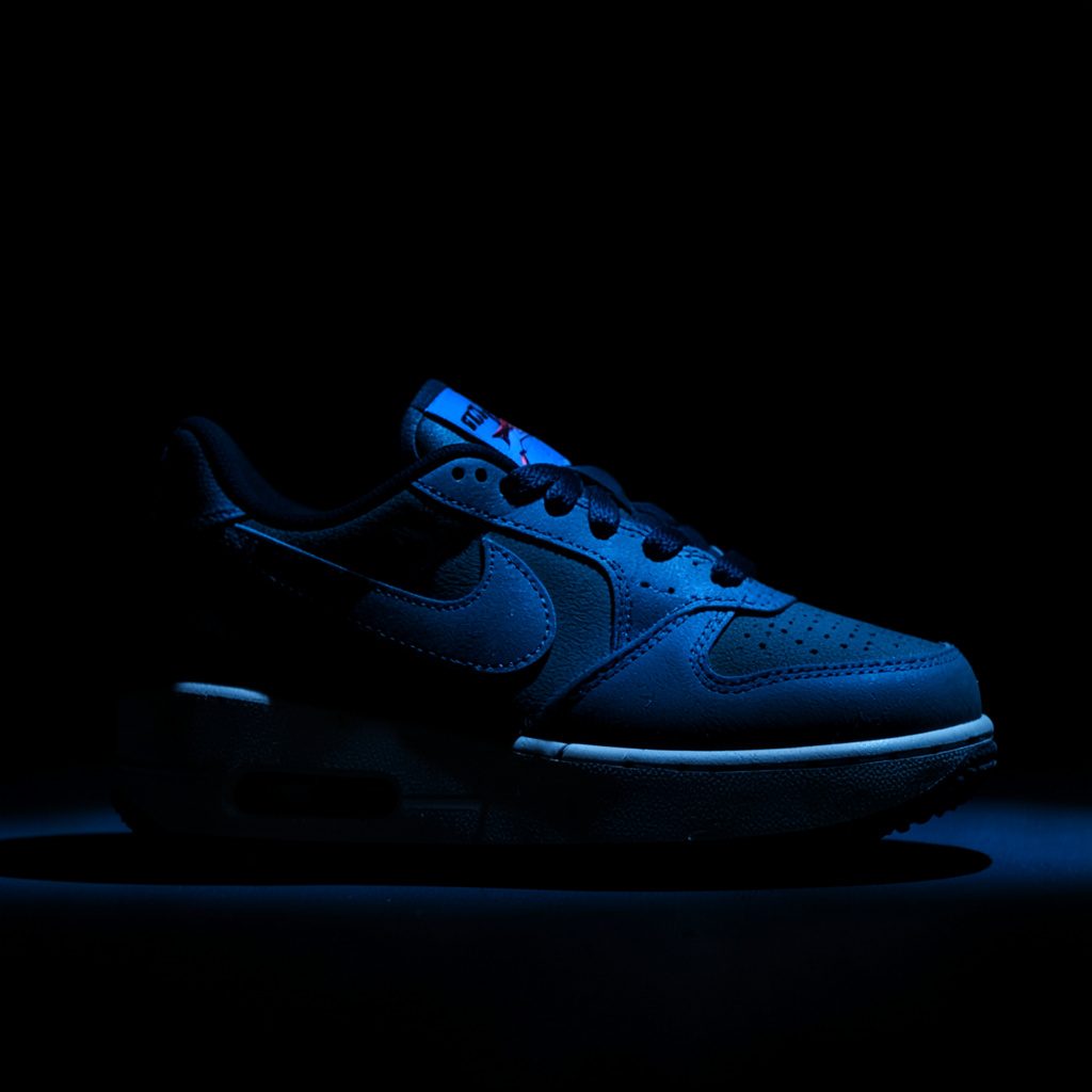 Nike Air Max 90 in een sfeervolle, low-key setting met diepe schaduwen en een warme ondertoon