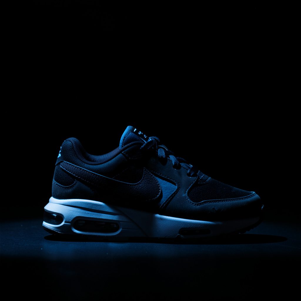Dames Nike sneakers in lichte kleurstelling, gefotografeerd tegen een donkere achtergrond