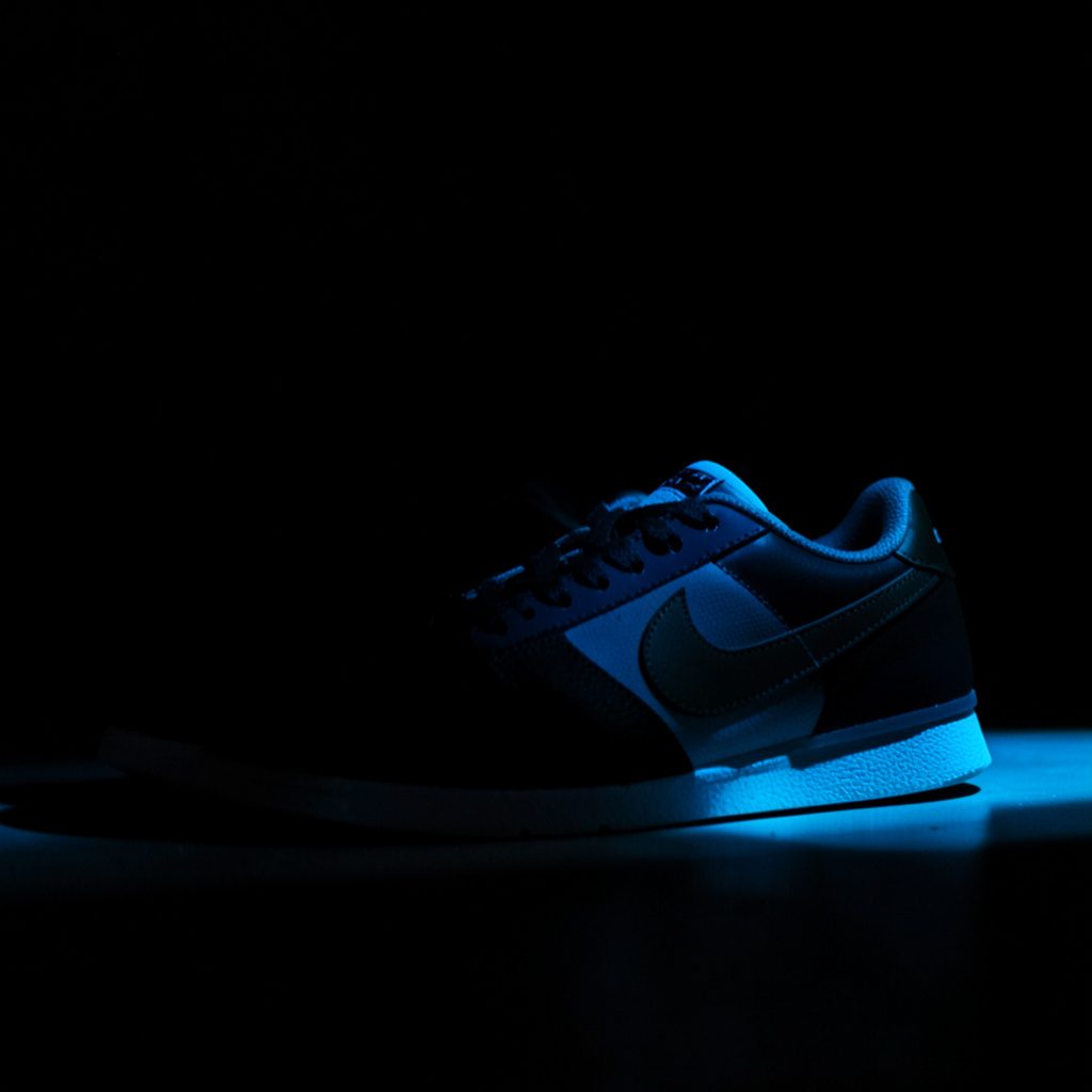 Nike sneakers in een donkere, stijlvolle compositie met warme accenten en zachte schaduwen