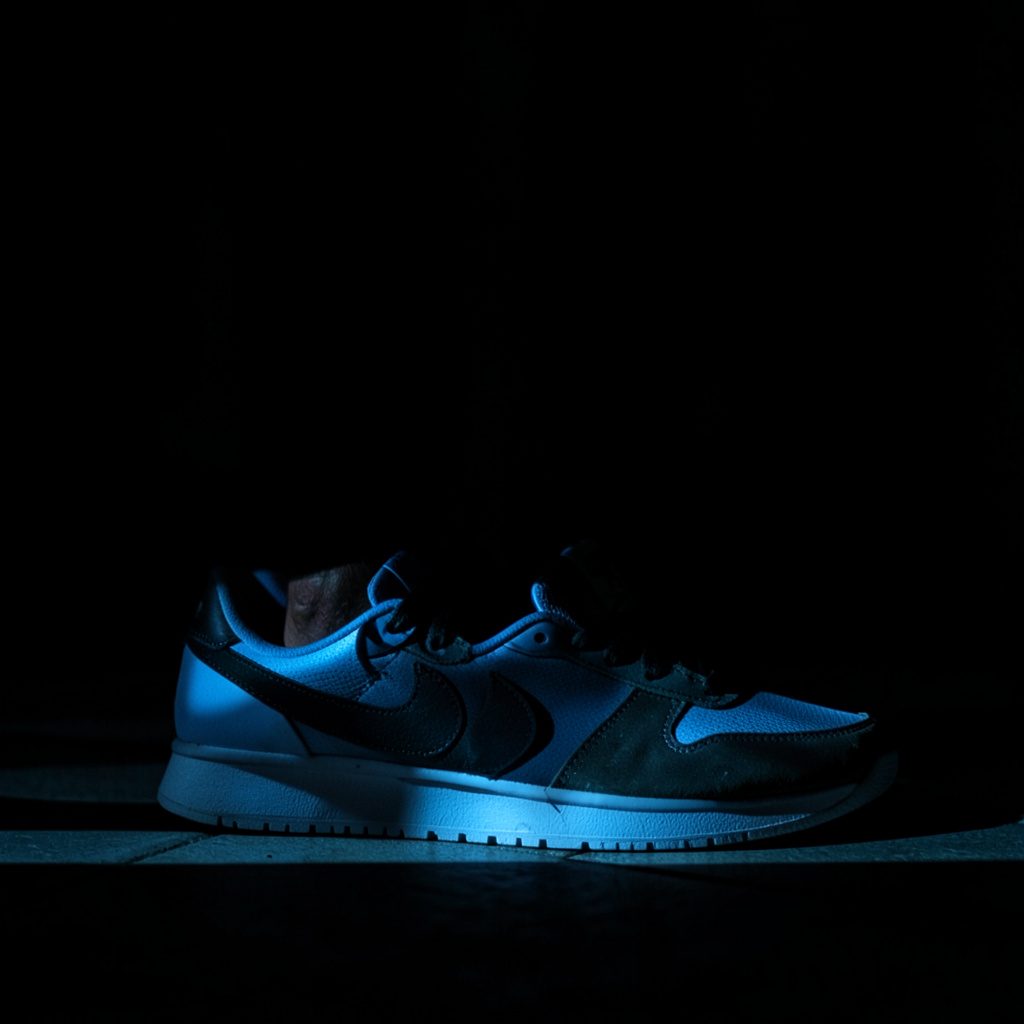 Nike sneakers voor heren op een donkere ondergrond met zacht licht en diepe schaduwen